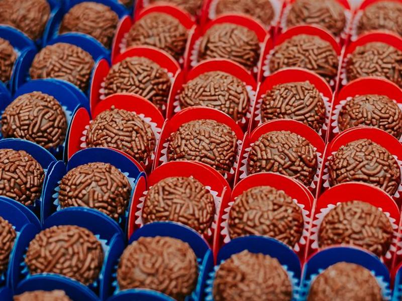 Bandeja com fileiras de brigadeiros em forminhas vermelhas e azuis